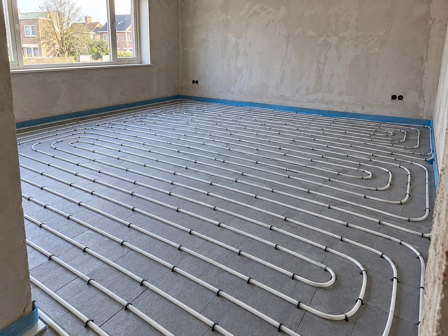 Vloerverwarming gelegd op isolatieplaten voor het storten van de dekvloer